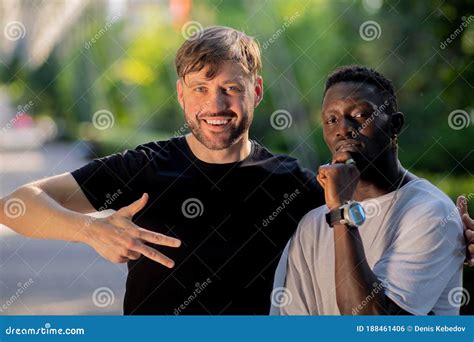 a black guy and a white guy hug and stare interracial friendship stock