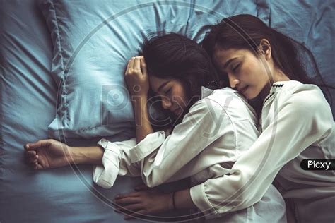 image of top view of two asian women sleeping on bed together lesbian