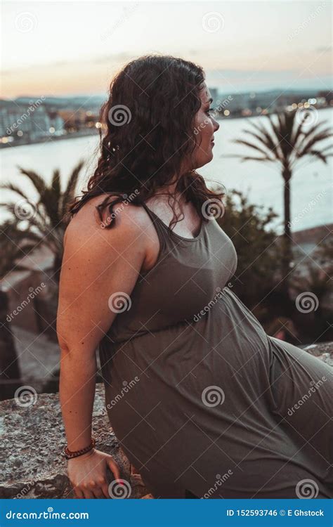 Brunette Curly Chubby Girl Wearing A Brown Dress Looking At The Sea At