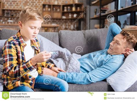 Caring Son Checking Temperature Of His Ill Father Stock