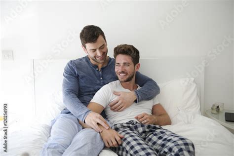 gay male couple at home relaxing in bed together acquista questa foto