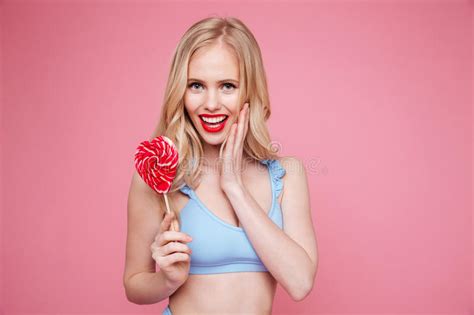 cute blonde woman in swimsuit posing with heart shaped lollipop stock