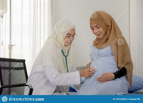 Pregnant Muslim Woman With Her Muslim Female Doctor In Clinic