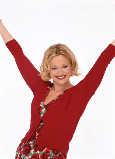 A Woman With Her Arms Up In The Air Smiling And Wearing A Red Top