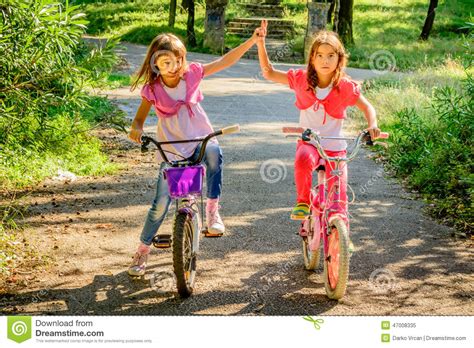due bambine che guidano le bici e che giocano a vicenda immagine stock immagine di altro