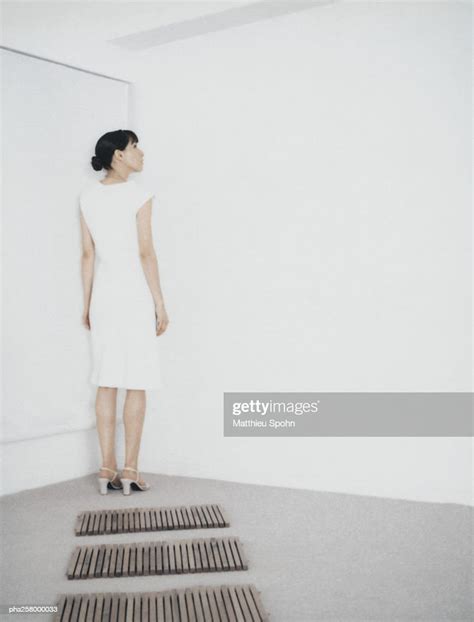 Woman Standing In Corner Of Room At End Of Path Of Wooden Rectangles
