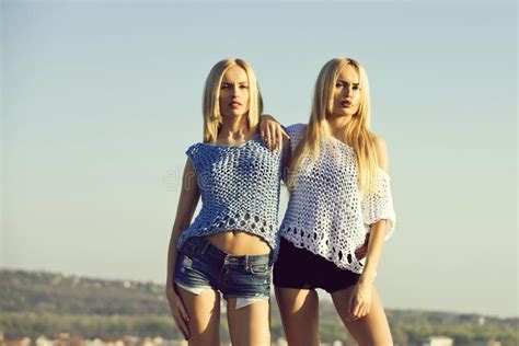 twin sisters with blond hair fashionable makeup and red