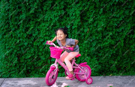 premium photo cute little asian girl riding a bicycle to exercise in