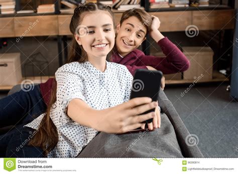 happy teenager couple taking selfie on smartphone and