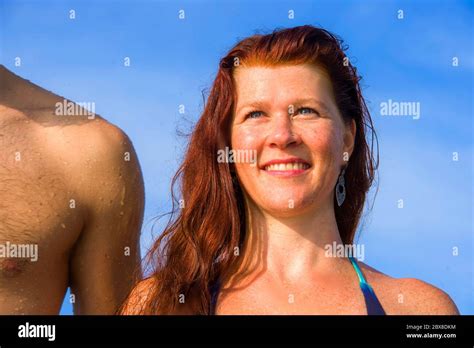 Young Beautiful And Happy Couple On The Beach Withl Red Hair Woman In