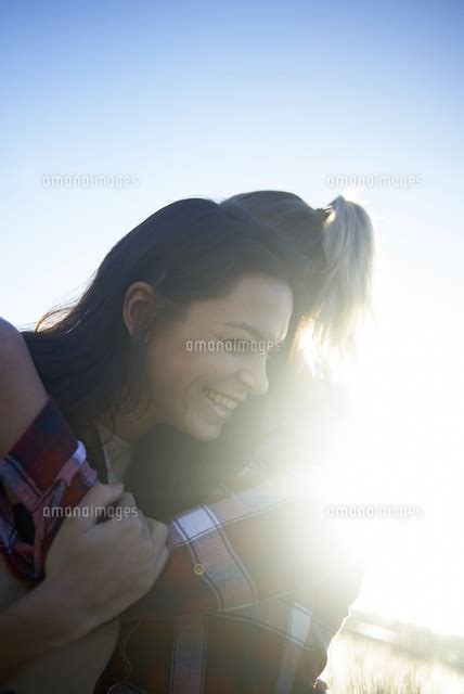 Cheerful Lesbian Couple Embracing Against Sky During Sunset[11100103213