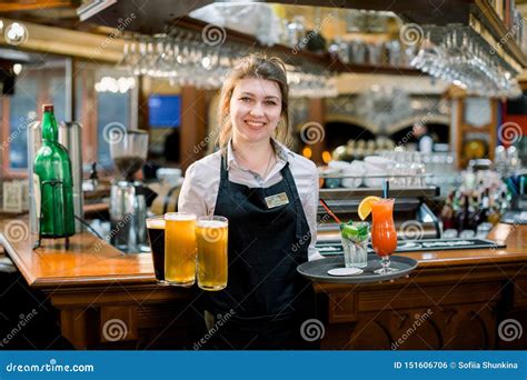 smiling friendly waitress serving a pint of draft beer in a pub