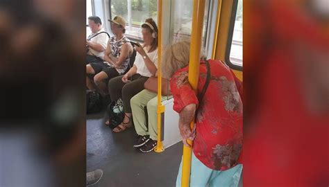 photo of elderly woman standing on train ignored by headphone wearing
