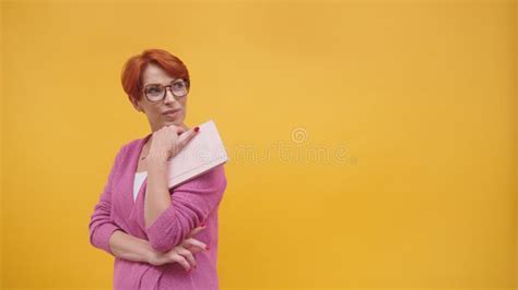 Mature Redhead Woman Holding Notebook Isolated On Orange Background