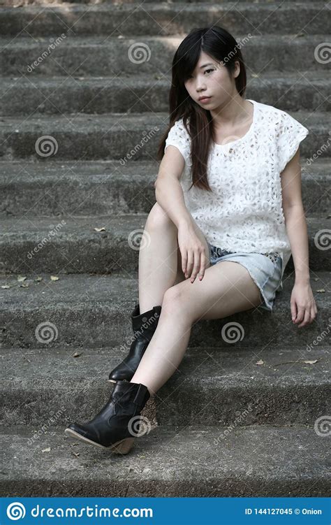 cute asian woman in a white top sitting down on steps