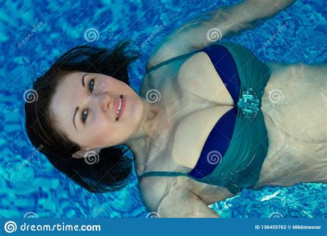 smiling woman with loose hair swimming backstroke in a bi