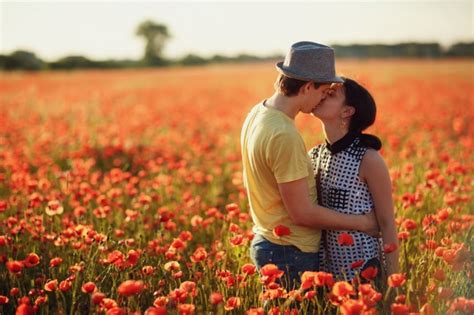 couple kissing in a field of red flowers photo premium