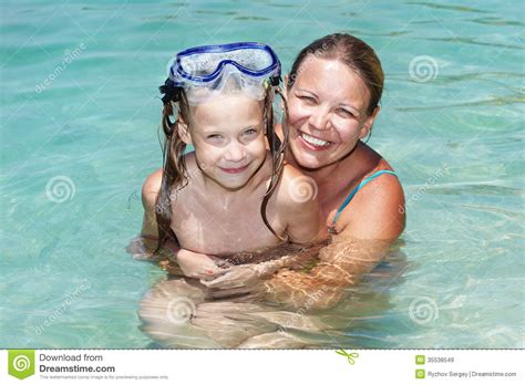 happy mom and daughter swimming in blue water royalty free