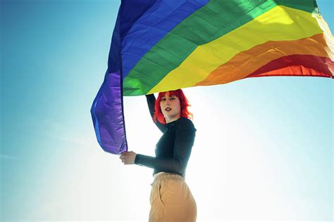 woman holding the gay rainbow flag on blue sky background happiness