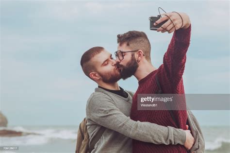 Gay Couple Taking Selfie While Kissing In Front Of The Sea Photo