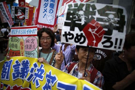 protesters raise placards during a rally against japan s prime minister shinzo abe s push to
