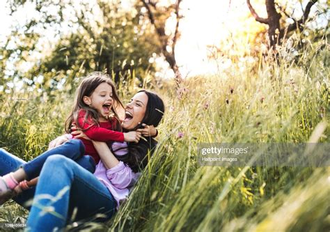 Happy Mother And Her Small Daughter Lying Down On The Grass In Spring