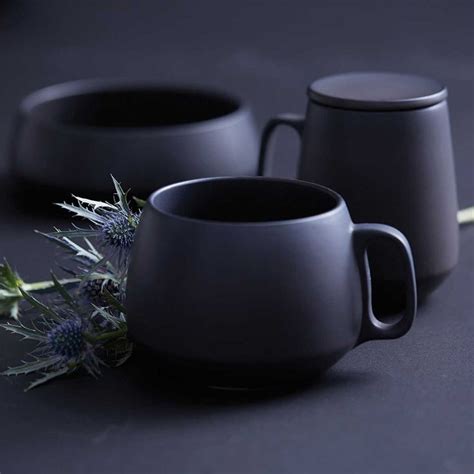 Two Black Mugs Sitting Next To Each Other On A Table
