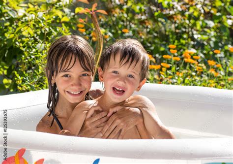 Older Sister Younger Brother Hugging In An Inflatable Pool In The