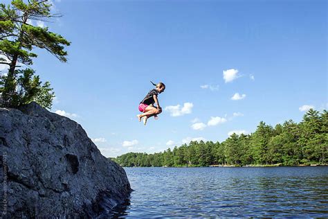 girl does a cannonball jump off a rock into the lake by cara dolan