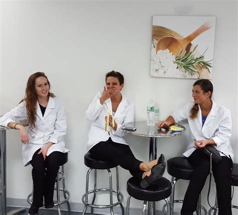 women  white lab coats sitting   table  black chairs