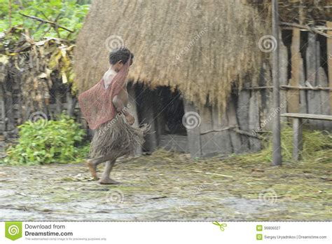 Papuan Girl From Dani Tribe Hurries To Hide From A Rain