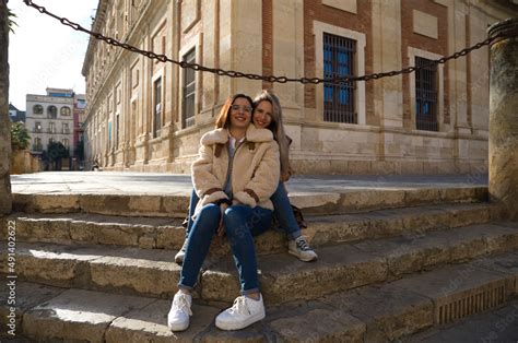 Lesbian Couple Sitting On The Steps Of A Pavement In A Monumental
