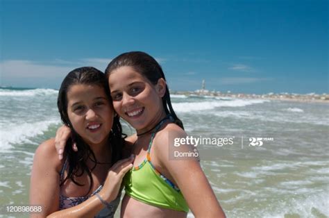 two girlfriends embracing on beach smiling port stock