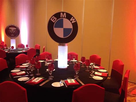 a round table set up with red chairs and black tables cloths for an event