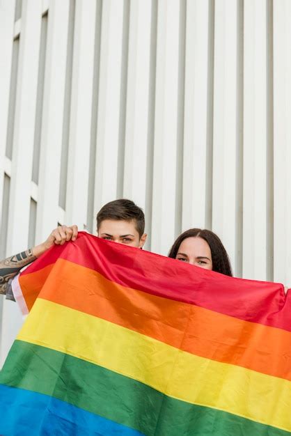 pareja de lesbianas se esconde detrás de la bandera lgbt foto gratis
