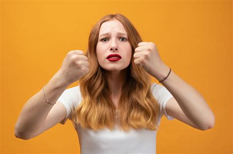 pretty girl with wavy redhead raising fists frustrated and furious