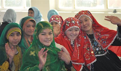 hazara girls wearing red traditional hijabs sitting next to tajik and pashtun girls in ghazni