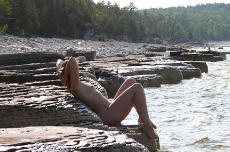 naked on the rocks by the river with hands behind head