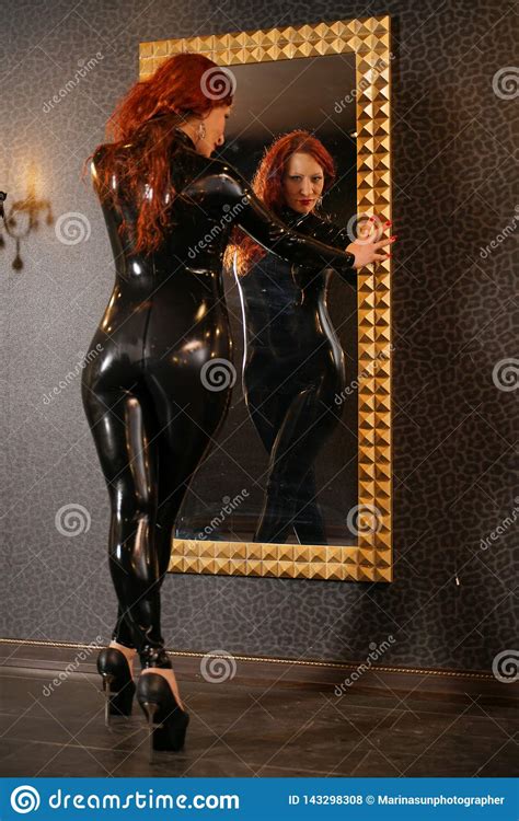 sexual fetish redhead woman wearing black latex rubber catsuit and