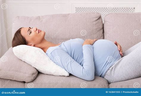 pregnant lady suffering  abdominal pain lying  sofa indoor stock