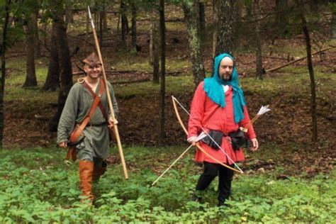 people dressed  medieval clothing walking   woods  bows  arrows