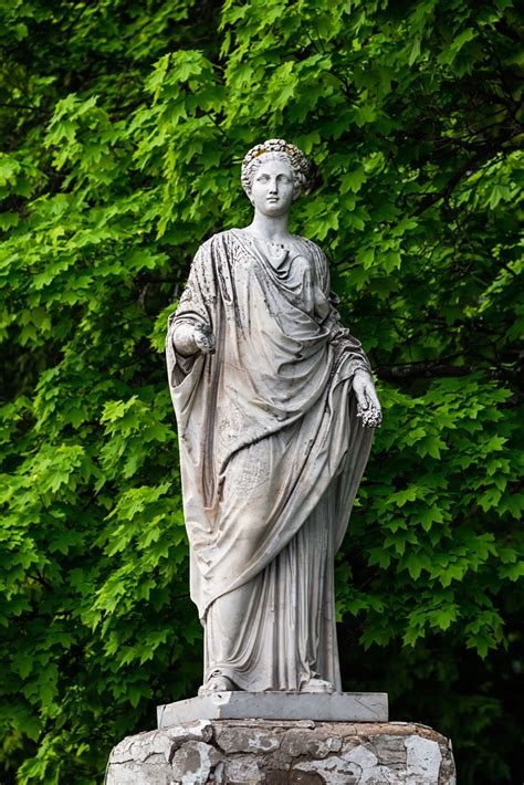 statue   woman standing  front   trees