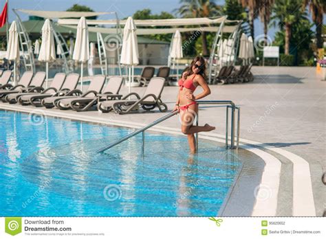 Girl In A Pink Bathing Suit Sunbathing By The Swimming Pool Sunny