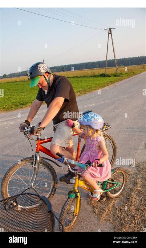 father and daughter riding bicycles on country road age 37 and 4