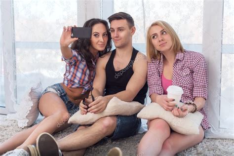 Two Girls And Guy Friends Taking Selfie Together Wearing