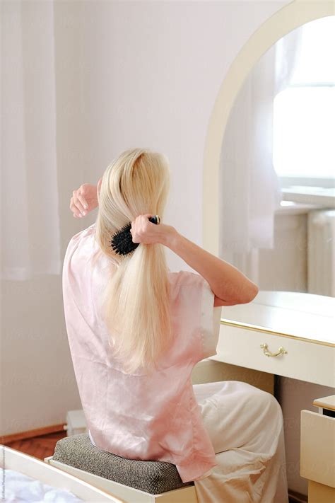 Blonde Girl Combing Her Hair In Front Of A Mirror Del Colaborador De