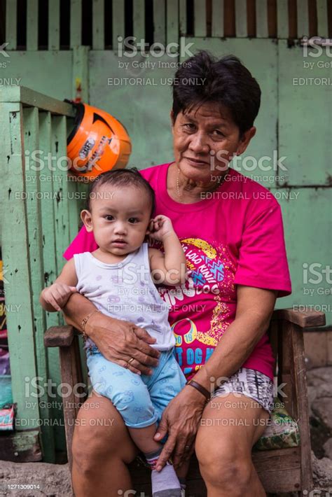 Filipino Grandmother Taking Care Of Grandson Sitting In Front Of Her