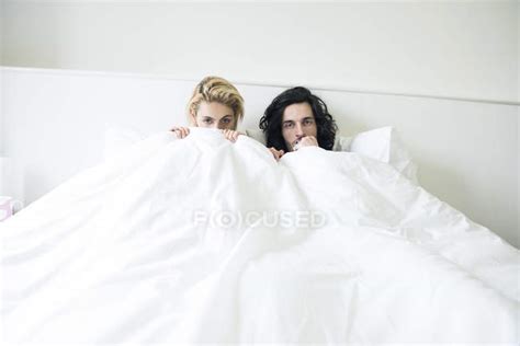 couple  bed playing peekaboo  camera people attractive stock photo
