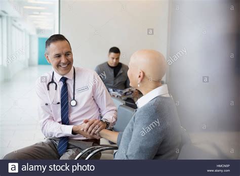 Smiling Male Doctor Holding Hands With Bald Female Cancer Patient In