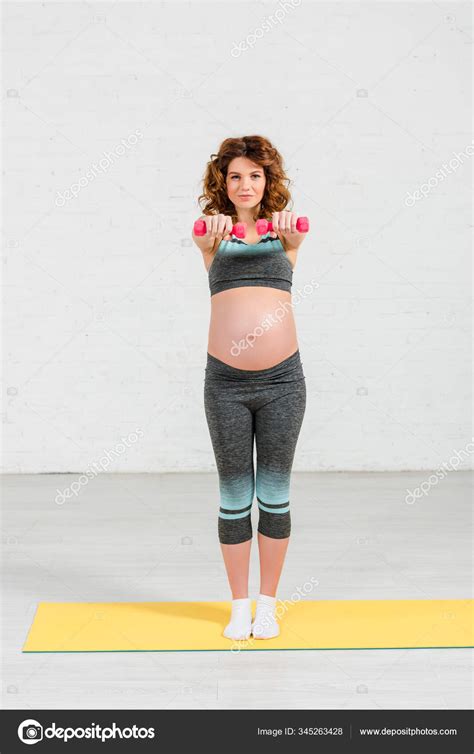 vacker gravid kvinna träning med hantlar träningsmatta